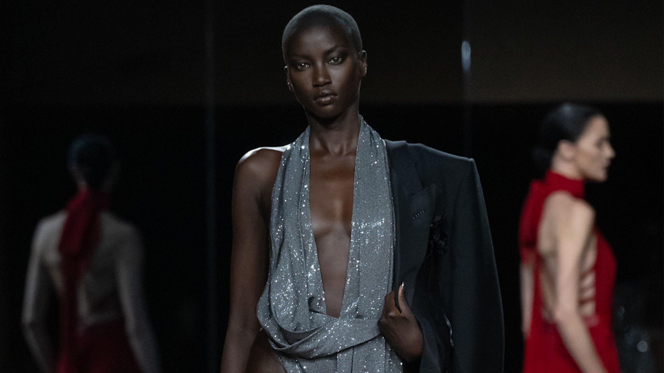 a model at the tom ford show wears a silver sequin bodysuit with a black blazer.