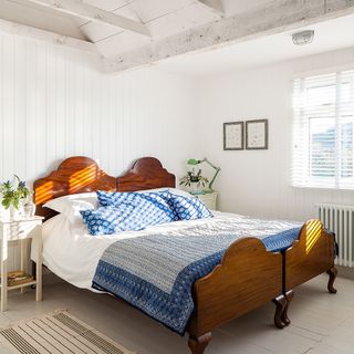 bedroom with white wooden flooring white walls and wooden bed