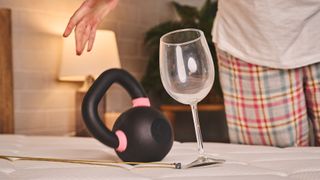 A kettlebell is dropped onto the Extra Firm side of the Plank Firm mattress, causing a wine glass to fall