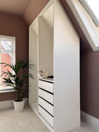 An attic room with a pitched ceiling and a white ikea pax wardrobe that doesn't maximize the space