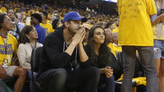 Actors Ashton Kutcher and Mila Kunis watch the Golden State Warriors game versus the Cleveland Cavaliers from their courtside seats during a time-out in the fourth quarter of Game 2 of the NBA Finals at Oracle Arena in Oakland, Calif., on Sunday, June 5,