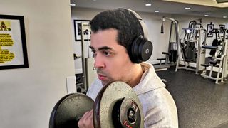 Alex Bracetti performing a biceps curl while wearing the Raycon Fitness Headphones