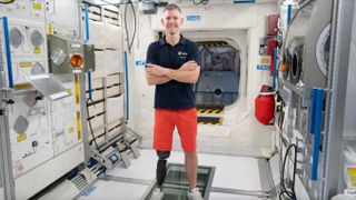 John McFall stands in a mockup International Space Station module.