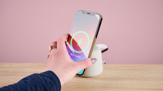 A woman is placing an iPhone onto a wireless charger.