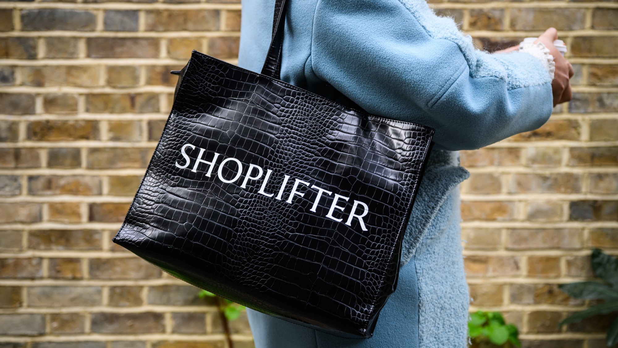  A woman with a bag on her shoulder reading "SHOPLIFTER" 