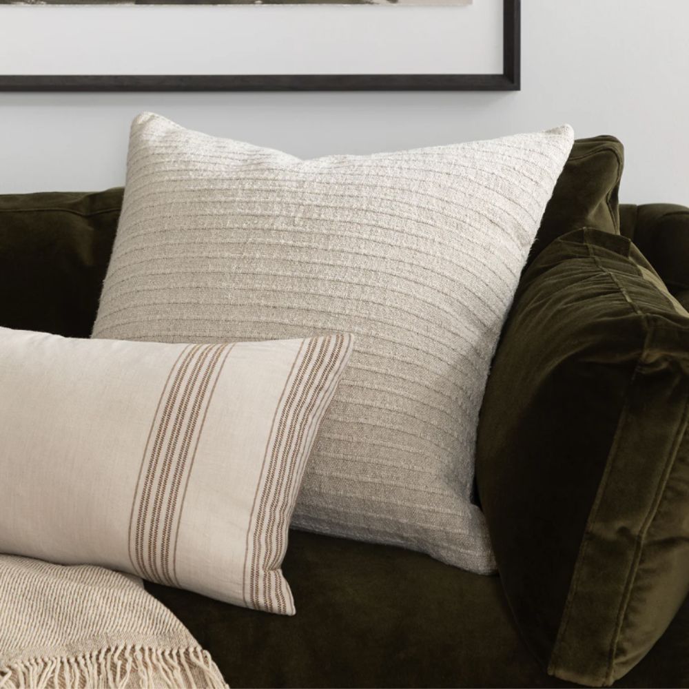 Two cream cushions on a dark green velvet sofa