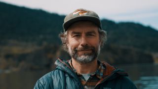 Photographer Corey Arnold standing in front of forest