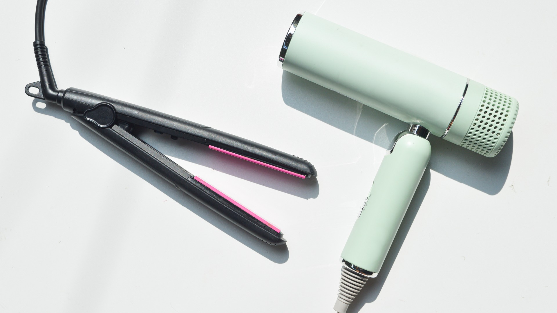 a light green blow dryer and a black flat iron