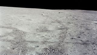 a view of the lunar surface showing a golf ball in a crater and a makeshift javelin sitting beside it