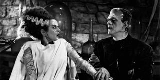 The Bride of Frankenstein looks shocked as she sits next to Frankenstein.