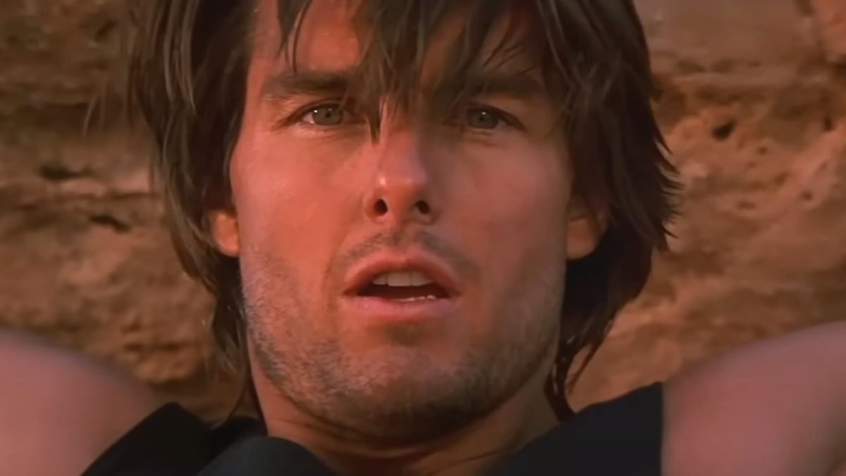 Tom Cruise props himself up in a crevace with a look of concern in Mission: Impossible 2.