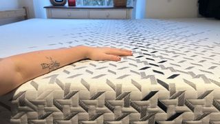 A mattress tester's arm resting on the surface of the Nectar Luxe mattress