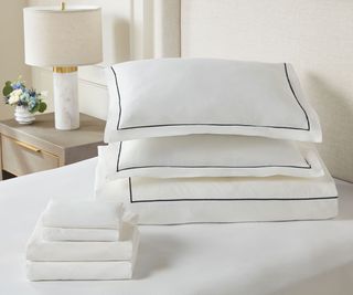 Hotel linens on a white bed against a white wall.