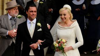 Helen George as Trxie Franklin and Olly Rix as Matthew Aylward on their wedding day wearing a wedding dress and suit in Call the Midwife season 12 finale