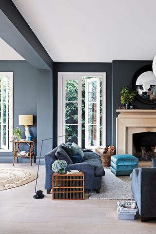 Dark blue living room with white ceiling, blue sofa and stone fireplace