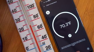 A Google Pixel 8 Pro measuring temperature next to a thermometer