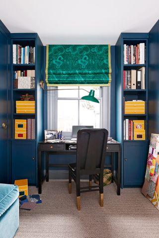 Home office in a closet painted blue with built in storage