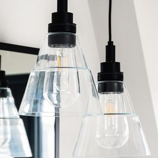 A trio of powder-coated matt black pendant light fixtures with clear glass lightbulbs