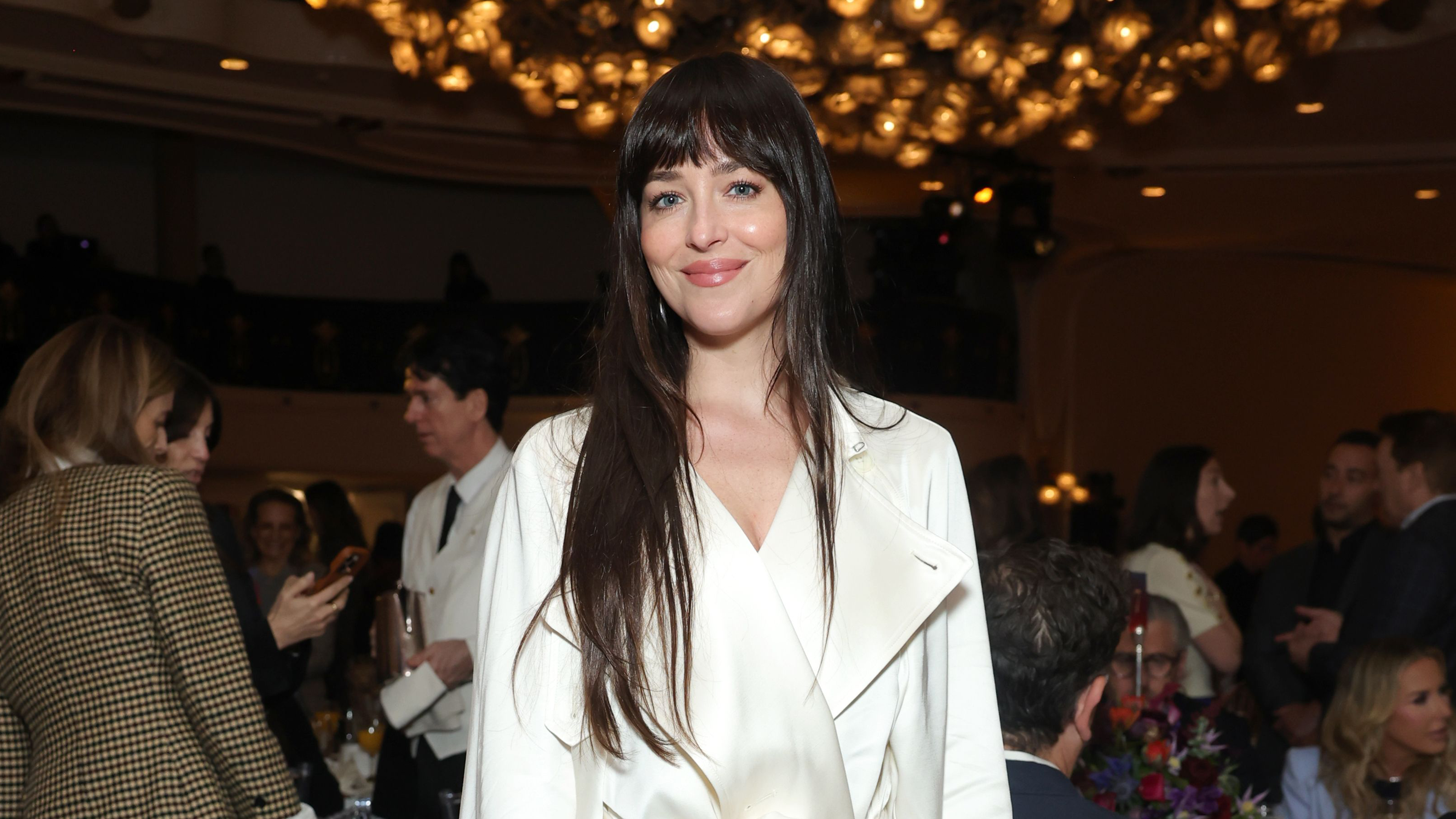 Dakota Johnson wearing a cream satin trench coat