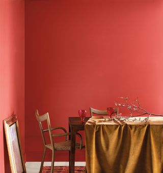 A dining room painted in a warm and bright red with a dressed dining table