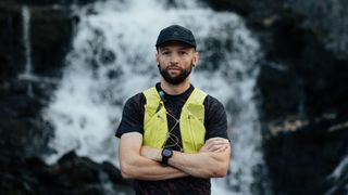 A photo of Jake Catterall standing in front of a waterfall