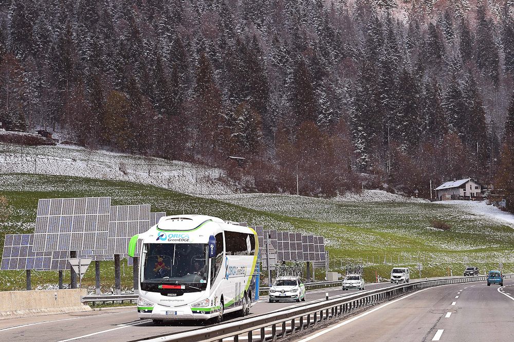 The Orica-Greenedge bus travels along roads with fresh snow in the trees