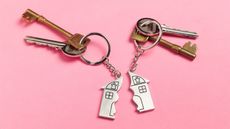 Two sets of house keys on a pink background