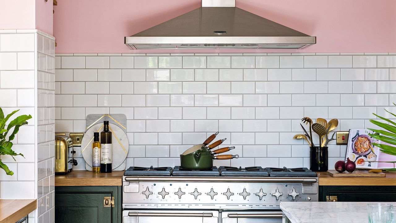 Open plan kitchen with pink walls, black Shaker style kitchen units, and rustic vintage furniture