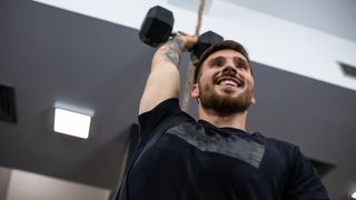 Man holding dumbbell above his head