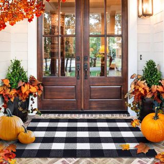 front porch decorated for fall with pumpkins and fall leaves