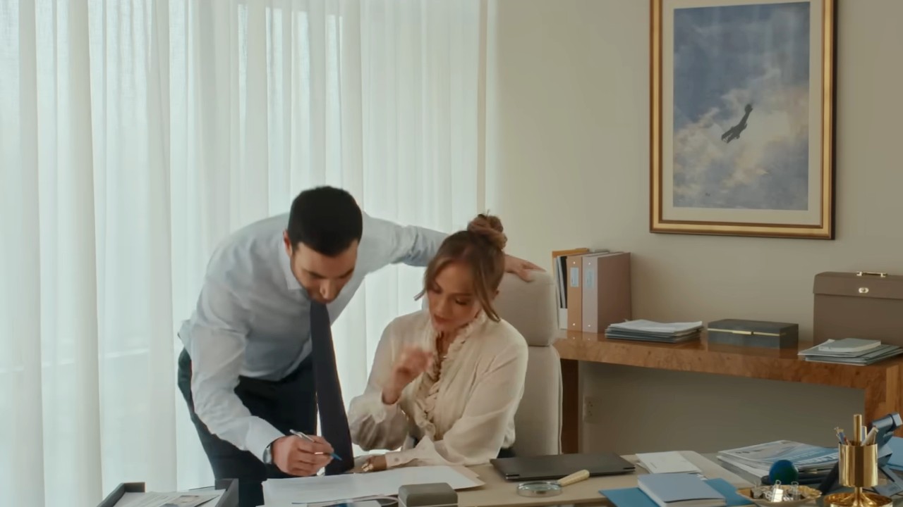 Jennifer Lopez and Brett Goldstein signing papers in Office Romance.