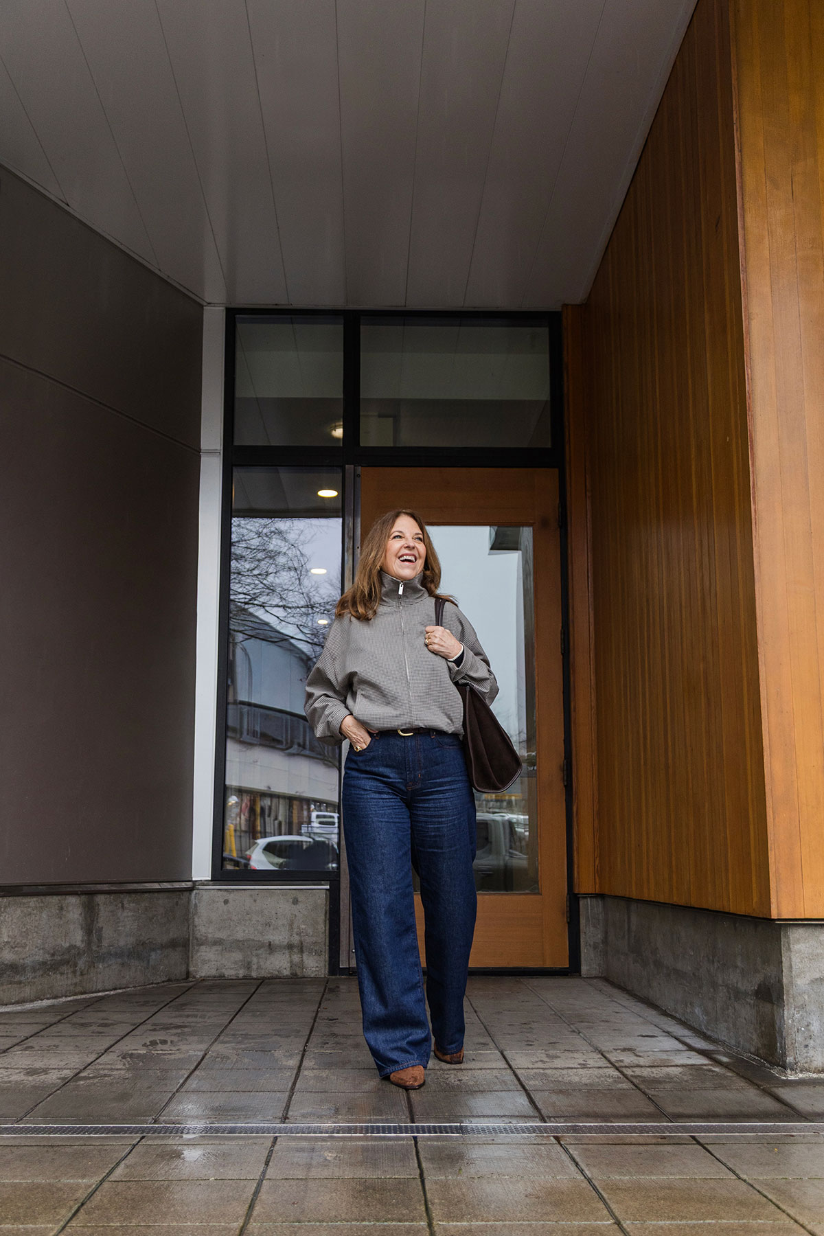 A former Nordstrom stylist wearing indigo jeans and a funnel-neck jacket.