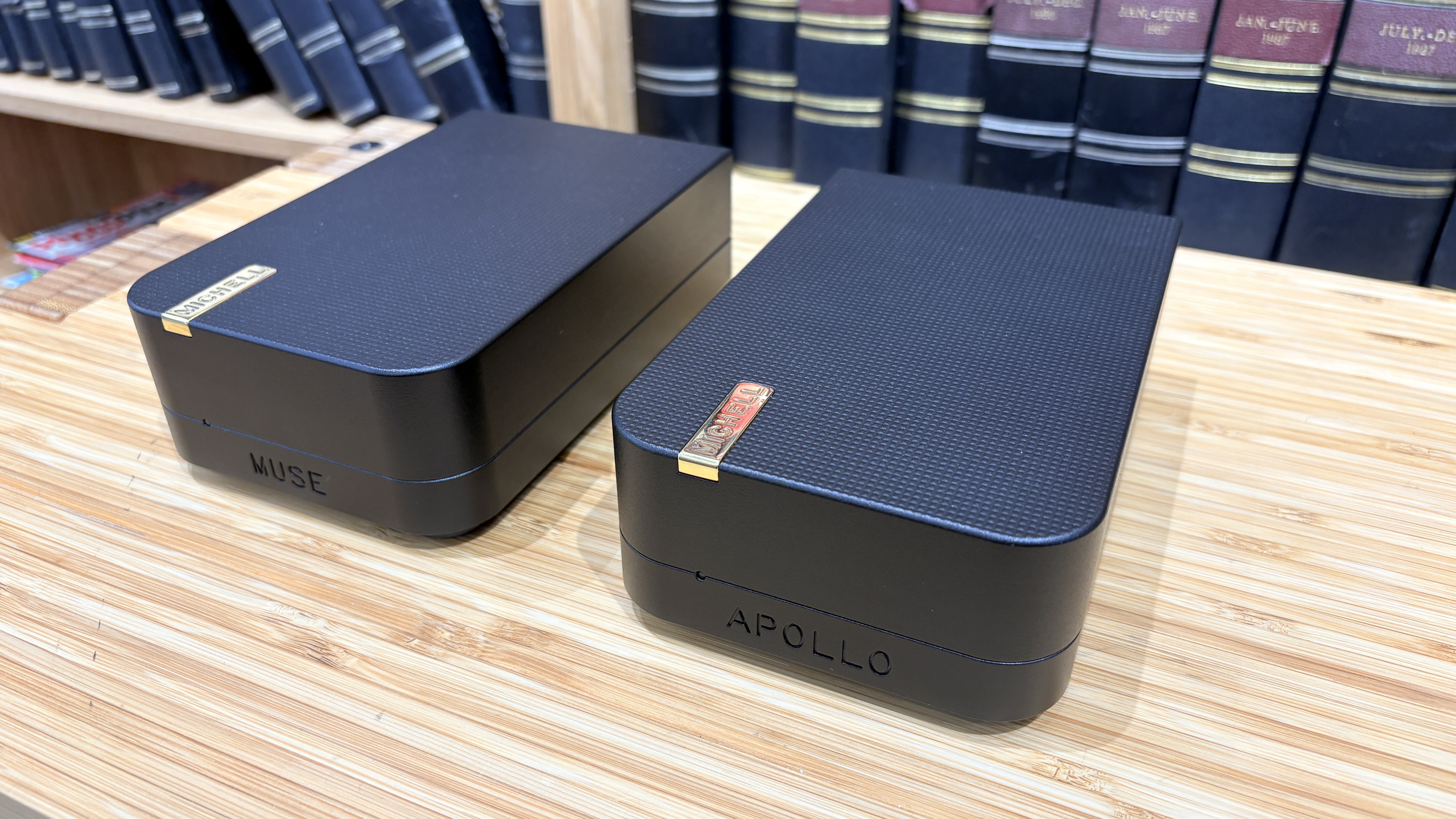 Michell Apollo phono stage and Muse power supply on wooden hi-fi rack in front of bookcase