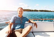 Portrait of a mature man in his 50s on a boat. He is smiling and looking at the camera.