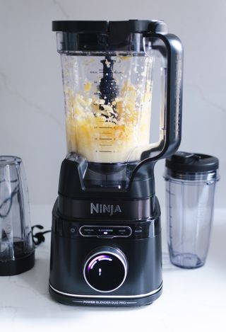 Ninja Detect Duo blending a smoothie with orange fruit pieces in milk