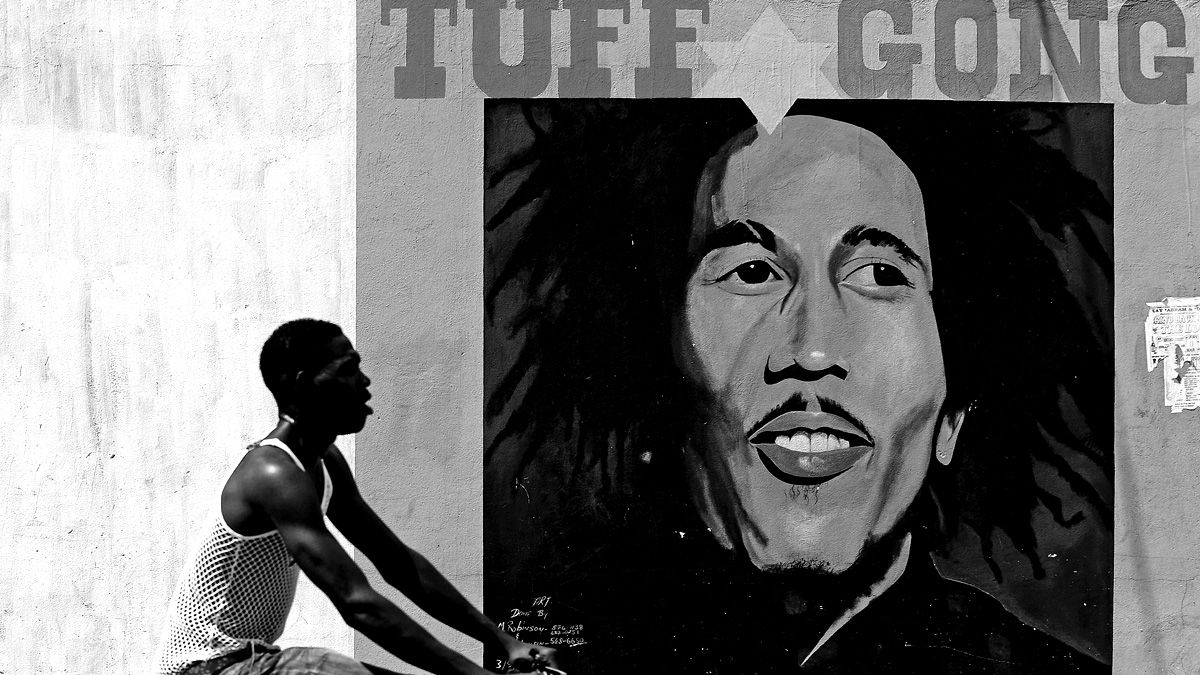 A man pedals past a mural of late musician Bob Marley in Kingston on February 8, 2009. Marley, who was born in 1945 and died in 1981, remains the most widely known and revered performer of re