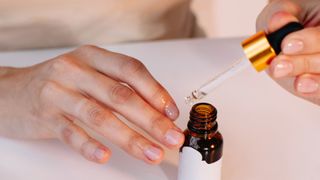 A close up of someone applying cuticle oil to their nails