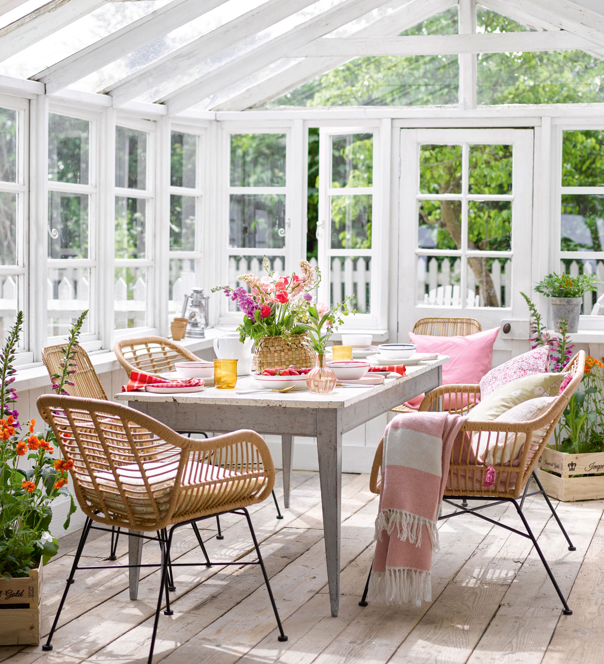 White conservatory with wooden dining table and rattan chairs