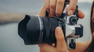 OM System OM-5 II camera held vertically in photographer's hands