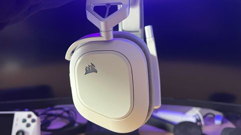 Corsair HS80 Max gaming headset being held in front of a monitor