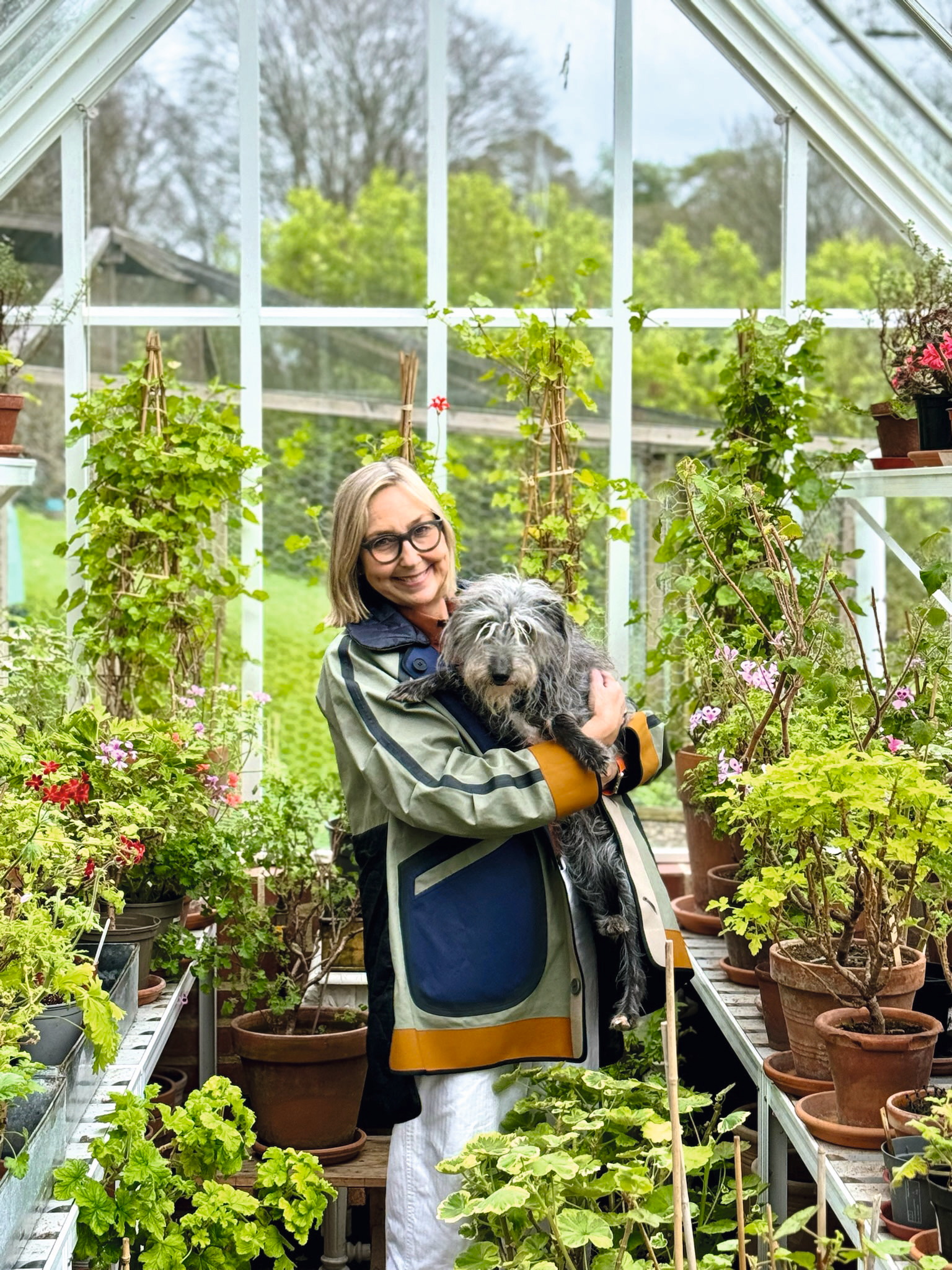Cath Kidston in a greenhouse cuddling a dachshund