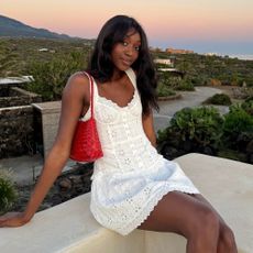 Influencer @emmanuellek_ wears a white mini broderie dress with a red woven shoulder bag.