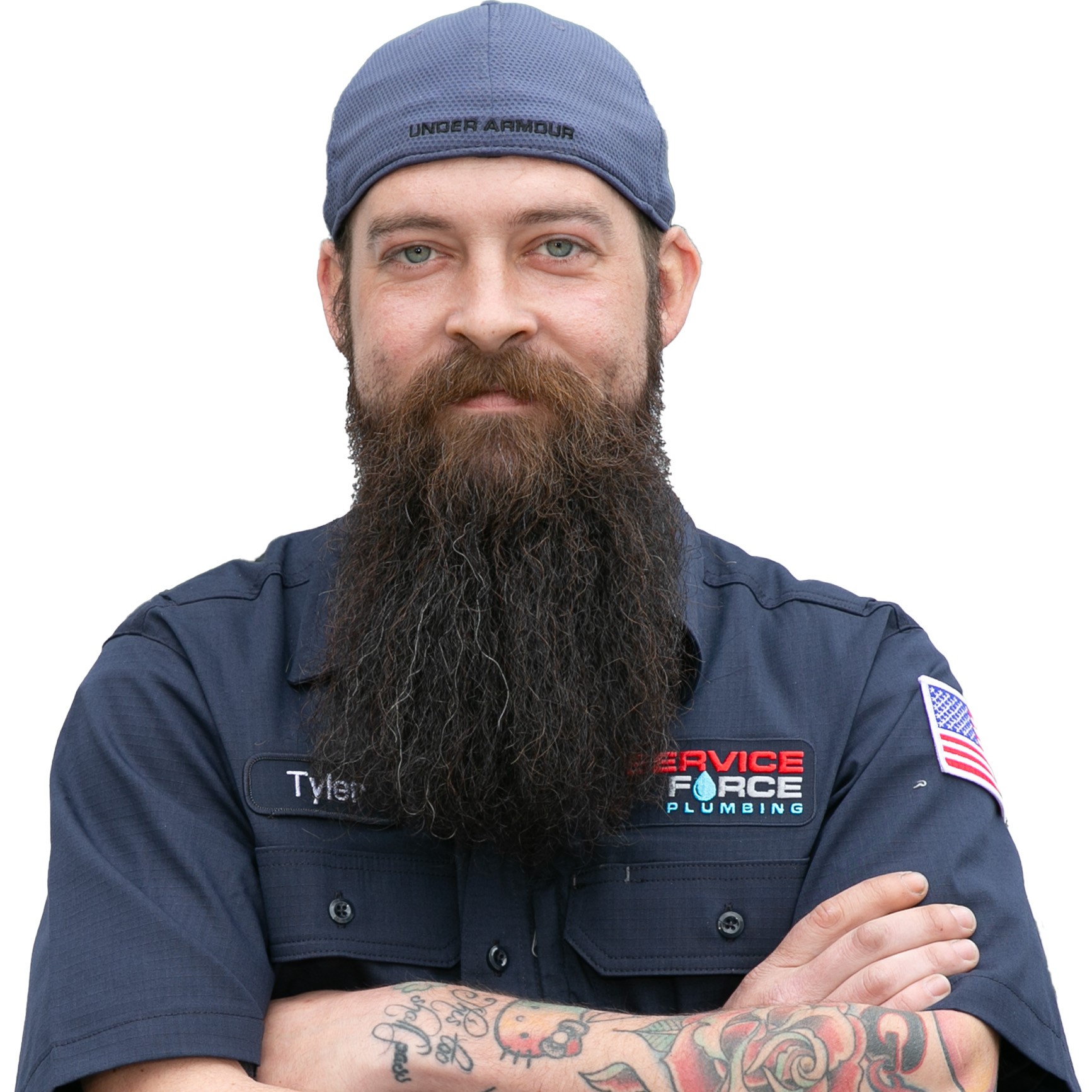 Tyler is a white man with a long brown beard. He is pictured with a blue fleece winter hat and a button-down dark blue short-sleeved work shirt with a red and blue Service Force Plumbing logo.