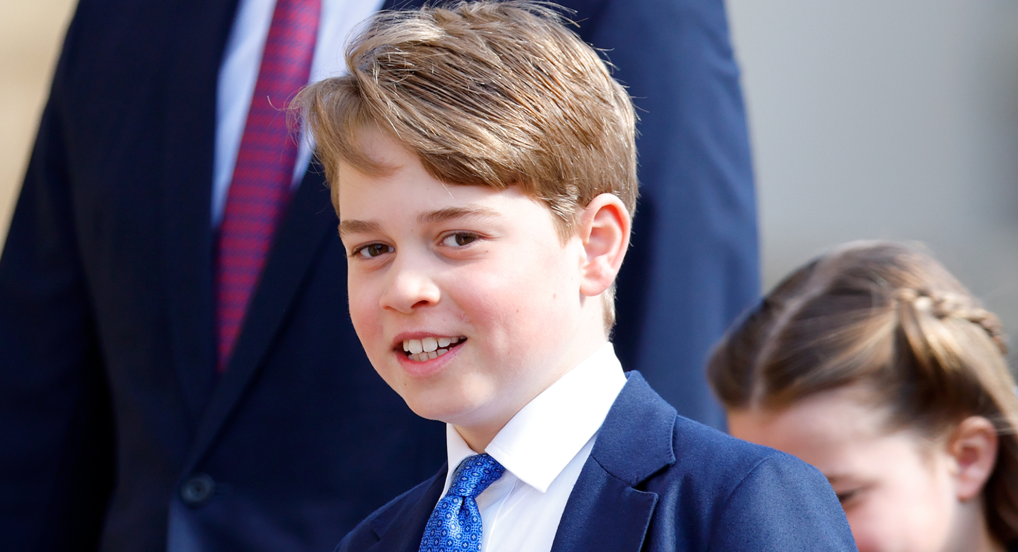 Prince George wears a navy suit, a white shirt, and a blue tie