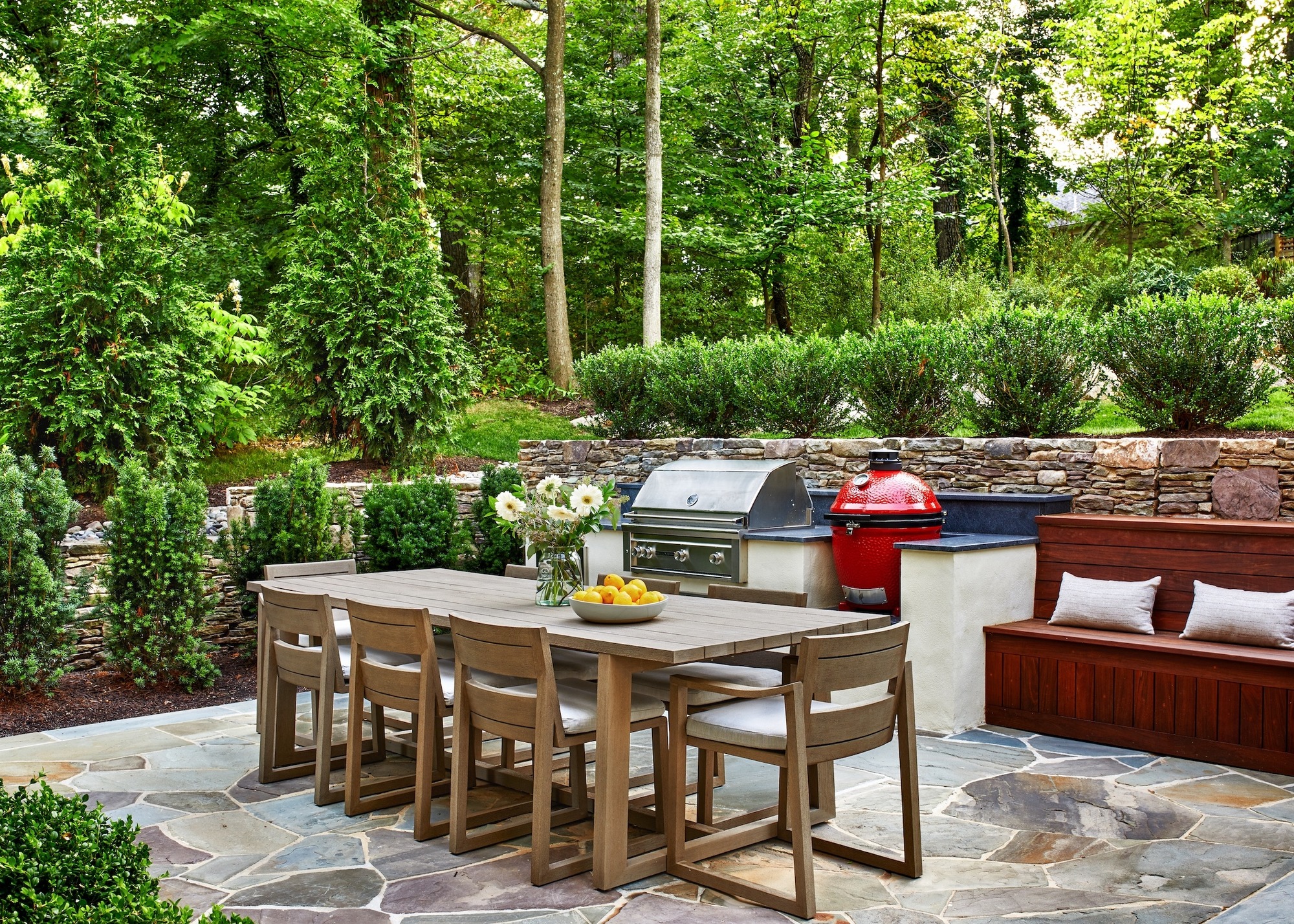 outdoor kitchen and dining area on a patio with garden surrounding