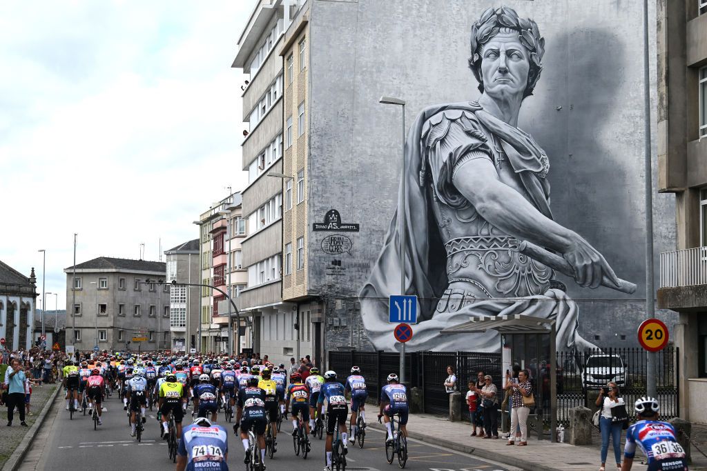LUGO SPAIN AUGUST 30 A general view of the peloton passing wallmural while fans cheer prior to the La Vuelta 79th Tour of Spain 2024 Stage 13 a 176km stage from Lugo to Puerto de Ancares 1659m UCIWT on August 30 2024 in Lugo Spain Photo by Dario BelingheriGetty Images