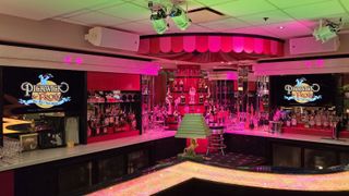 The bar at Hilarities Theatre in a low pink light. 