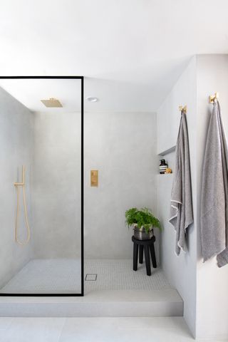 grey plaster shower room with stool and plant by LH. Designs