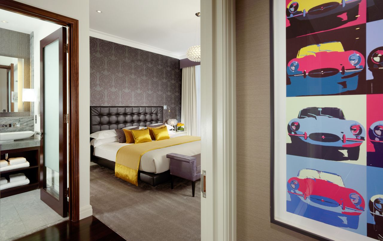 The bedroom featuring a walk-in bathroom, double bed, and an andy warhol style mural of E-type jaaaaaags
