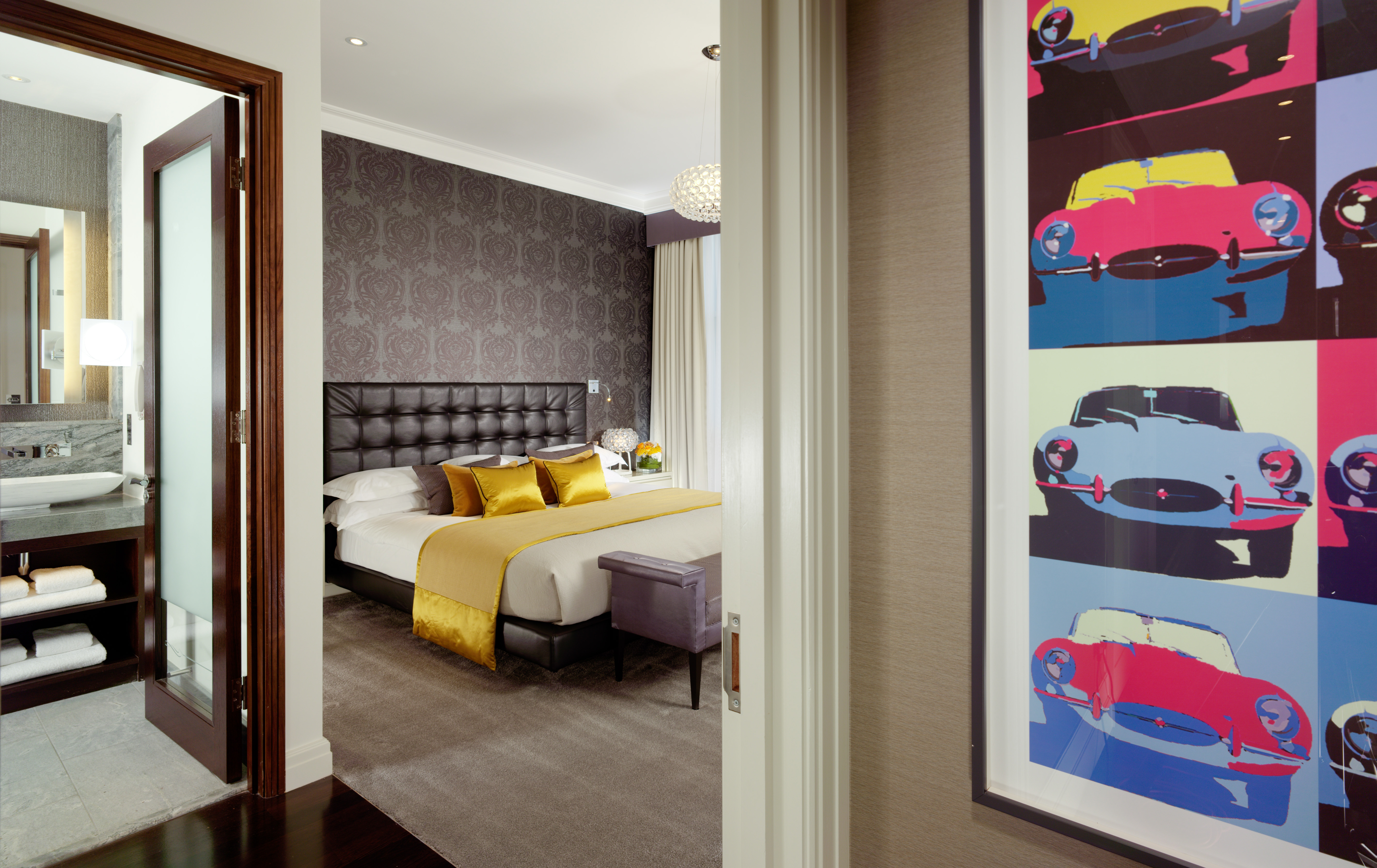 The bedroom featuring a walk-in bathroom, double bed, and an andy warhol style mural of E-type jaaaaaags